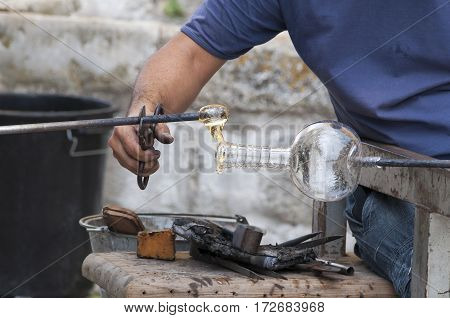 Craftsman glassblower working in a piece of liquid glass