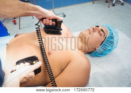 Male surgeon resuscitating an unconscious patient with a defibrillator at the hospital