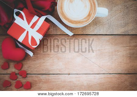 Red rosesheartgift box and cup of coffee on wooden background with copy space.Valentines Day background concept Wedding day.Top view vintage tone
