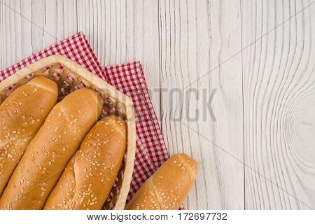 Buns in a wicker basket on old wooden table. Top view.