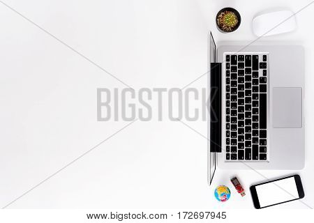 Modern White office desk table with laptopblank screen smart phonemouse and flashdrive.Top view with copy space.Working desk table concept.
