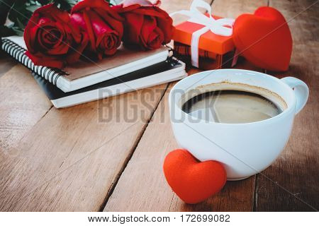 Cup of coffee red roseheart and notebook on wooden background with copy space.Close up.Valentines Day background concept Wedding day.Top view vintage tone