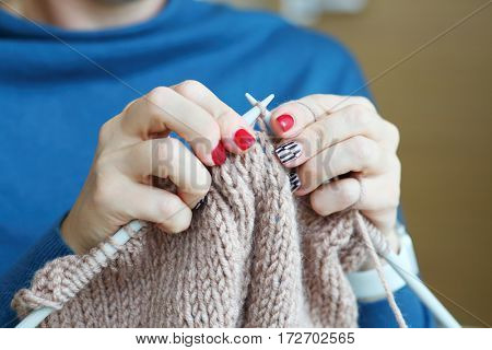 Hands of knitting woman in blue dress, close up view, noface