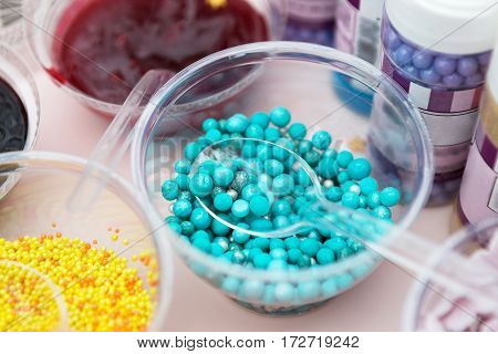 Ice cream treats and toppings sale. Rainbow sprinkles, stars, non pareil and glitter cupcake decorations, bright blue. Closeup in plastic plates with spoons. Confectionery store