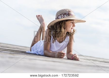 Girl with hat lying on the wooden walkway