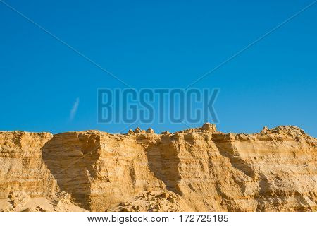 cliff of the yellow orange brown sand soil clay under the bright sunny day with deep blue sky.