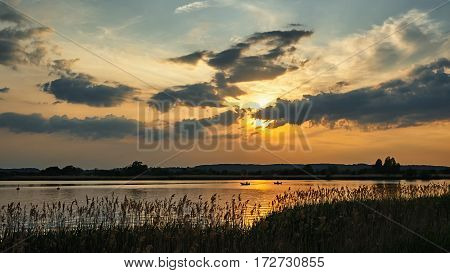 Sunset over the boats on the river. Yellow sun breaks through the clouds.