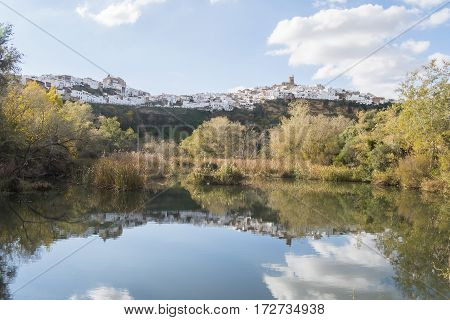 Panoramic of Arcos de la Frontera reflected in the river white town built on a rock along Guadalete river in the province of Cadiz Spain
