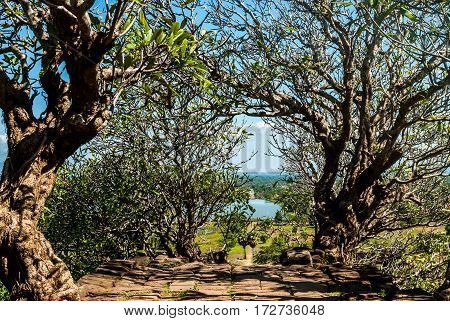 Wat Phu in Southern Laos - The path up the mountain, with stairs in the shade of beautiful trees -view of the baray in the distance