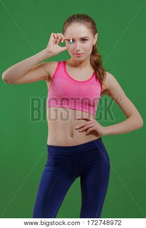 Young girl at gym showing pills. Shallow depth of field. Focus on pill.