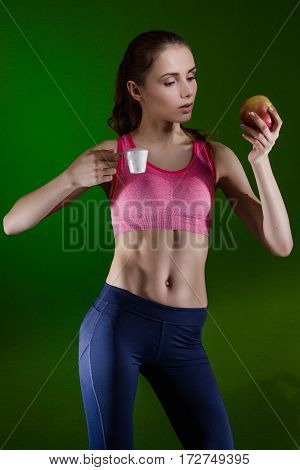 Caucasian girl that chooses to eat sports nutrition or apple. Choice concept.