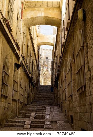 En empty street of the old city in Jerusalem Israel. Stone walls with barred windows stairs leading up