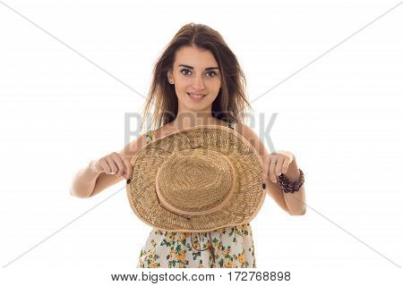 young pretty brunette girl in sarafan with floral pattern and straw hat with wide brim smiling on camera isolated on white