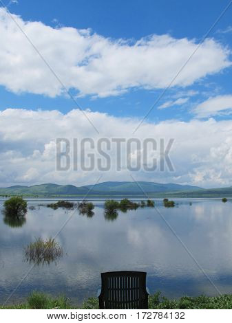 empty chair isolated in a lake reflecting breathtaking clouds