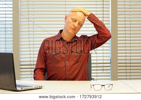 middle age balding man relaxing neck - short break for exercise on chair in office