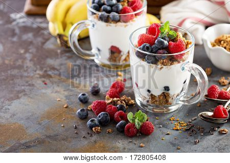 Granola yougurt parfait with fresh berries in glass mugs