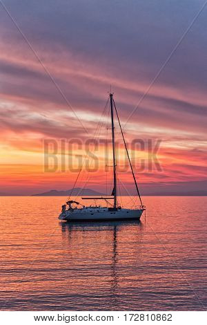 Sailboat sunset silhouette is a sailboat sailing along the water with a colorful purple and pink night sky in the background