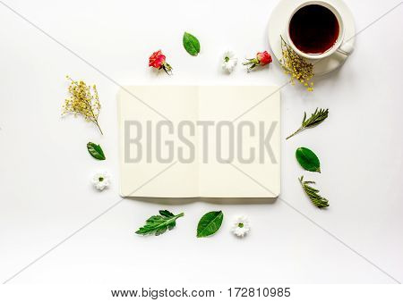 Floral flat lay with cup of coffee and opened copybook on white background top view mock up