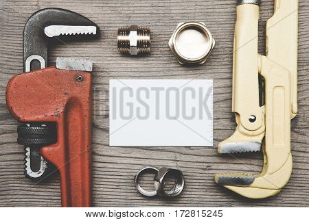 Pipes plumbing tools fittings and business card on the wooden surface background