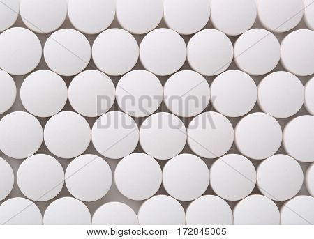 Top view of round white pills closeup sit on a table.