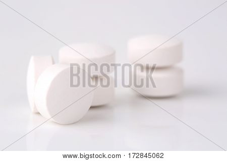 Round white pills closeup sit on a table.
