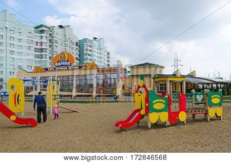 GOMEL BELARUS - APRIL 14 2016: Man with child are on modern children's playground with bright colored constructions in sleeping district on street Khatayevich Gomel Belarus