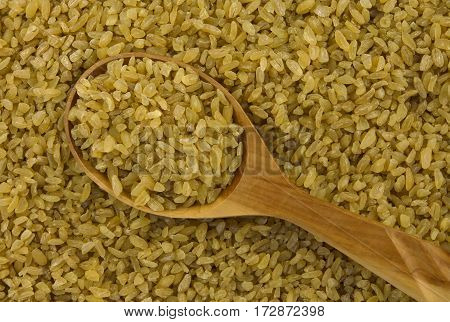 background of dry bulgur wheat with spoon from above