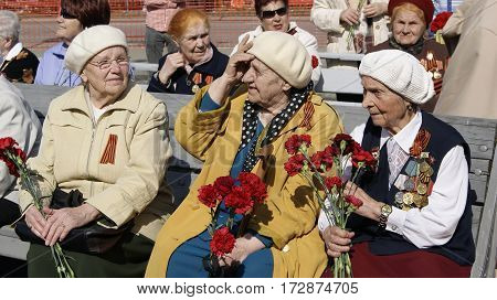 NOVOURALSK/ RUSSIA - MAY 9. Old women - veterans of the great Patriotic War with medals and bouquets of carnations on May 9, 2012 in city Novouralsk, Sverdlovsk region, Russia.