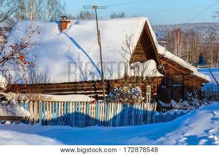 Rustic log house covered with snow. Russian old-believer village Visim in the low Middle Ural Mountains of Sverdlovsk region, Russia