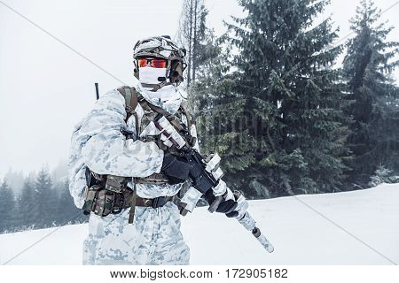 Winter arctic mountains warfare. Action in cold conditions. Trooper with weapons in forest somewhere above the Arctic Circle