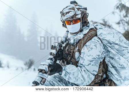 Winter arctic mountains warfare. Action in cold conditions. Trooper with weapons in forest somewhere above the Arctic Circle