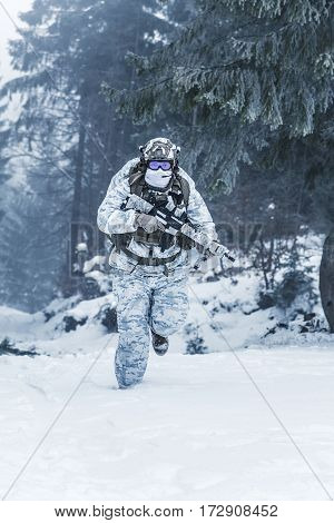 Winter arctic mountains warfare. Action in cold conditions. Trooper with weapons in forest somewhere above the Arctic Circle