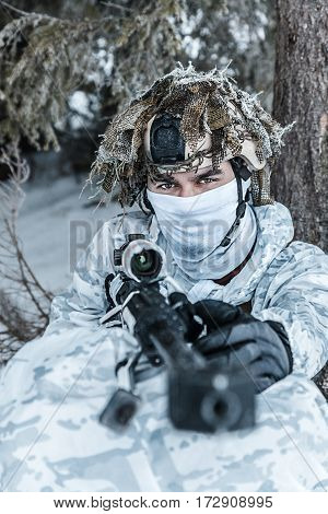 Winter arctic mountains warfare. Action in cold conditions. Sniper with weapons in forest somewhere above the Arctic Circle