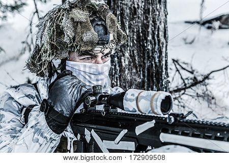 Winter arctic mountains warfare. Action in cold conditions. Sniper with weapons in forest somewhere above the Arctic Circle