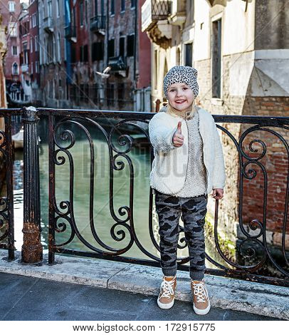 Venice. Off the Beaten Path. Full length portrait of modern child in Venice Italy in the winter showing thumbs up