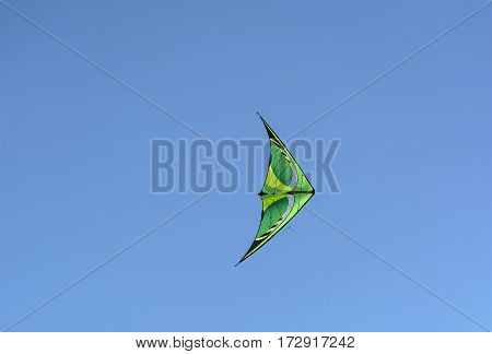 green with yellow kite floating in the blue sky Sunny day