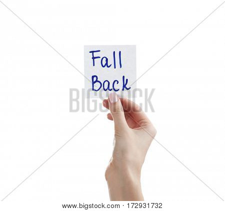 Female hand holding note with phrase FALL BACK on white background