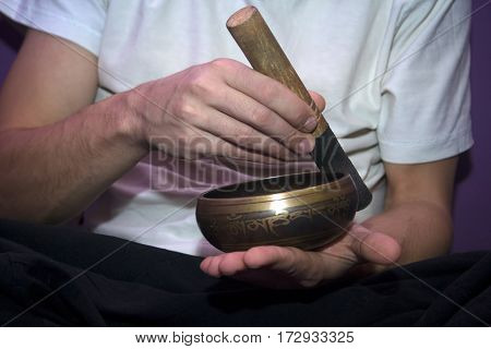 Man in white t-shirt playing on a singing bowl
