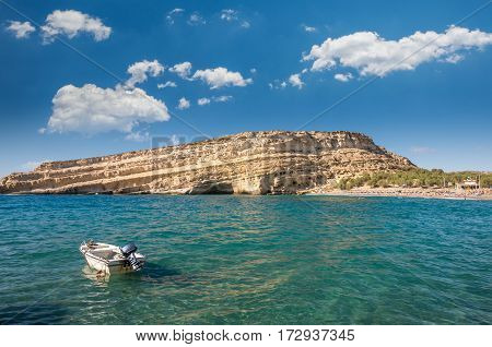 Matala beach on Crete island, Greece. Tourists relax and bath in crystal clear water of Matala in south of Creta. There are many caves near the beach.