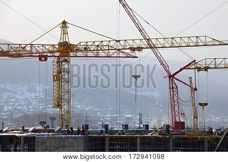 Workers are building a building by means of a tower crane