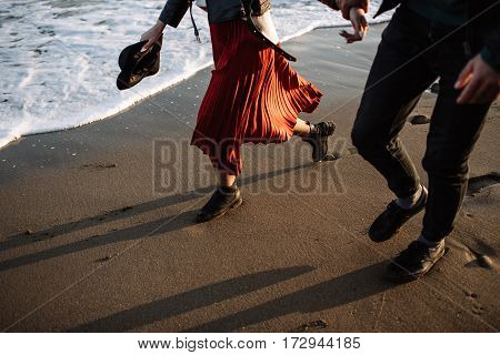 A guy and a girl running through the waves of the sea