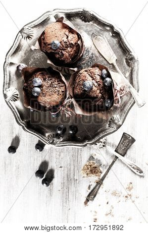 Chocolate cupcake on an antique silver tray with blueberry on the top. Delicious food with nice table-ware. Food concept.