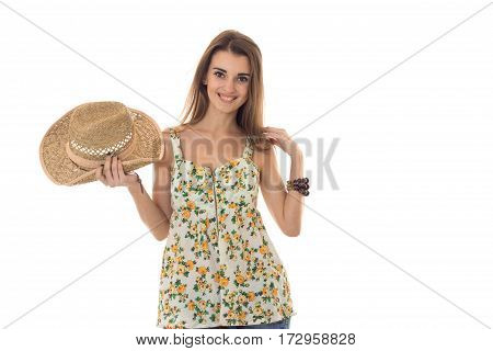 Happy brunette woman in sarafan with floral patter and straw hat posing and smiling on camera isolated on white