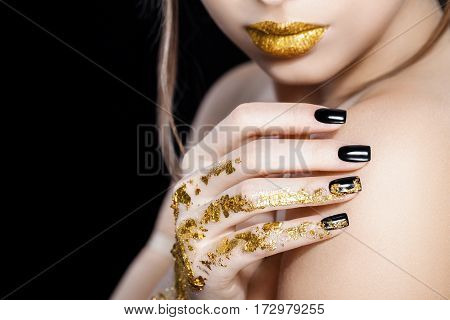 Beautiful Fashion woman model face portrait with gold lipstick and black nails. Glamour girl with bright makeup. Beauty female. Perfect skin and make up. Nail polish. Isolated on black