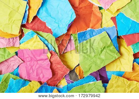 Surface covered with multiple colorful pieces of torn paper as an abstract background composition