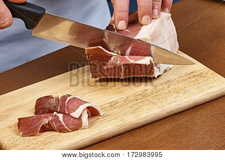 Dry cured ham thinly sliced Closeup on chef hands slices prosciutto Italian delicatessen dishes cooking process