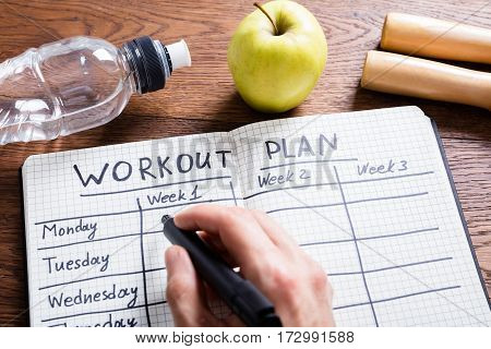 High Angle View Of A Workout Plan In Notebook At Wooden Desk