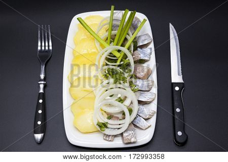 Dutch national appetizer, herring with onions.Tasty pieces of Icelandic herring with boiled potatoes and onions on the plate. National Icelandic snack Fat herring.