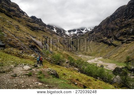 Hikers In Lost Valley In Glen Coe, Scotland. Mountain Landscape