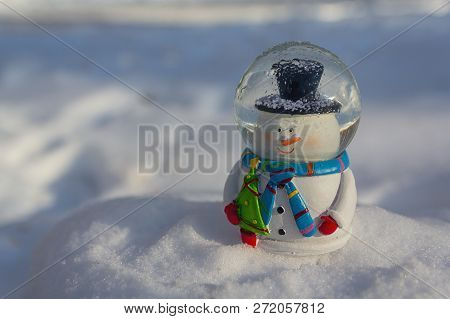 Cheerful Happy Toy Snowman On A Snowy Background. New Year
